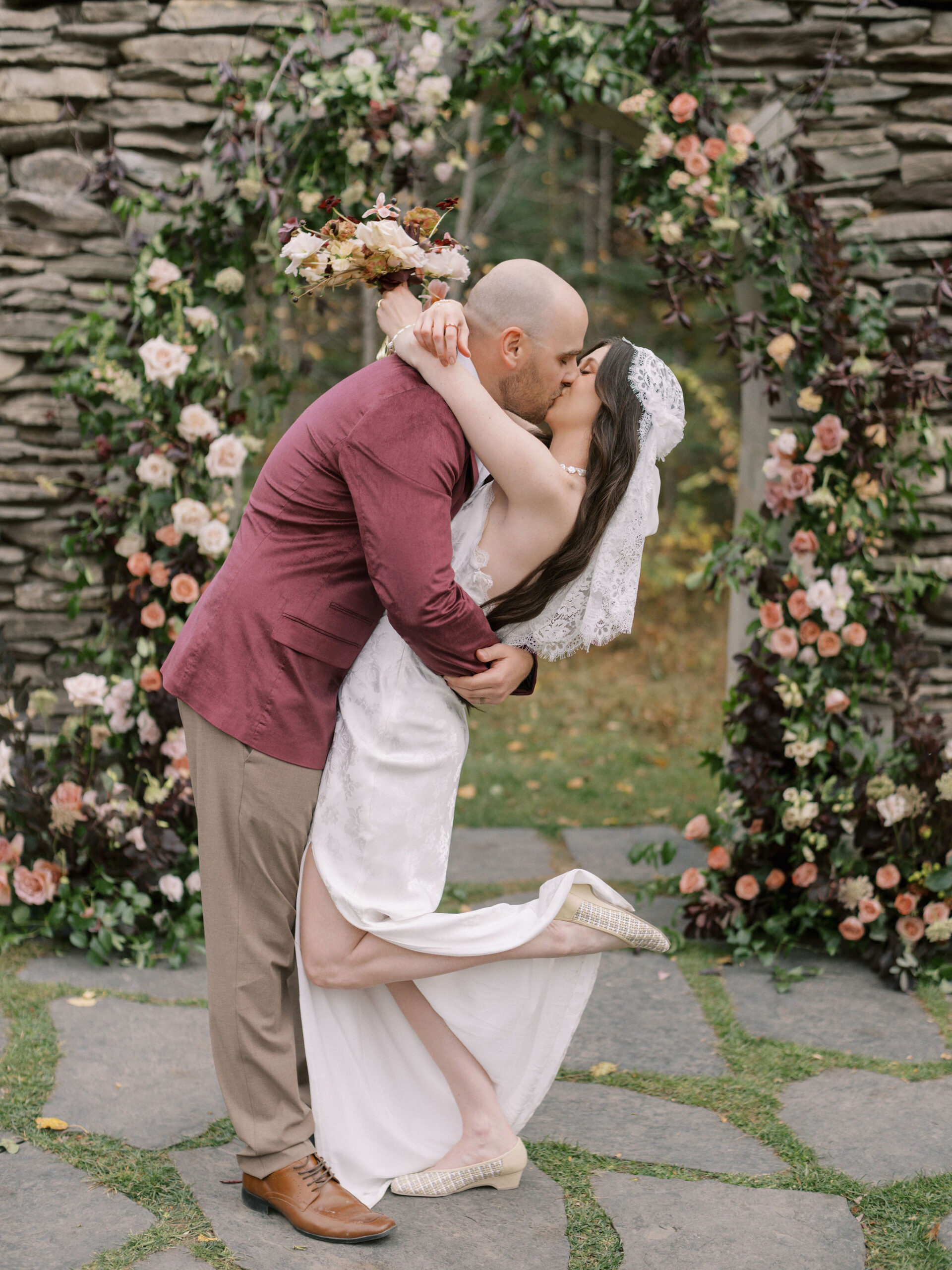 Newlyweds kissing i8n front of archway