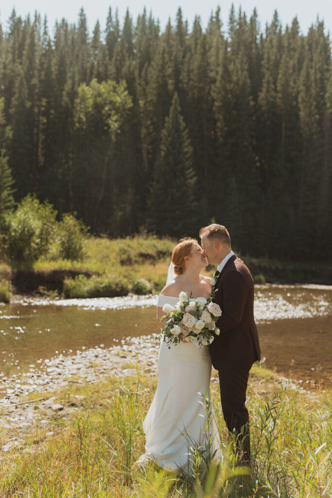 Newlyweds kissing by a lake
