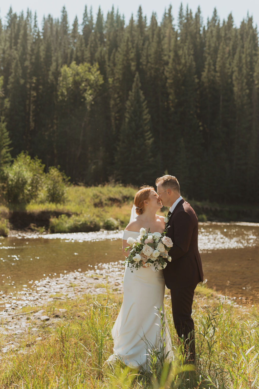 Newlyweds kissing by a lake
